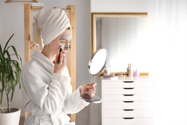 Fiatal nő alkalmazása agyag maszkot otthon - Fotó, kép