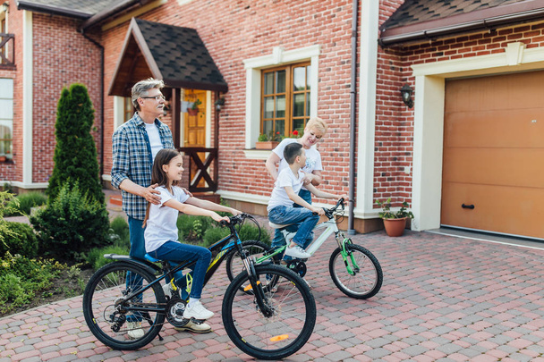 Szczęśliwi dziadkowie nauczając wnuki jeździć na rowerach - Zdjęcie, obraz