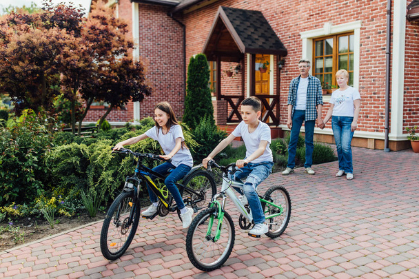 Happy grandparents teaching grandchildren to riding bikes - Valokuva, kuva