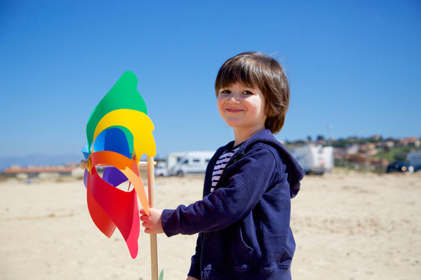 Gülümseyen küçük çocuk renkli fırıldak tutuyor - Fotoğraf, Görsel