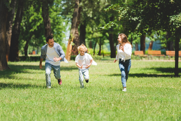 happy family in casual clothes running in park during daytime - Zdjęcie, obraz