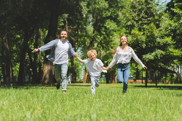 excited family holding hands and running in park during daytime - Foto, immagini
