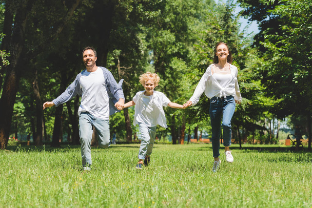 happy family holding hands and running in park during daytime - 写真・画像
