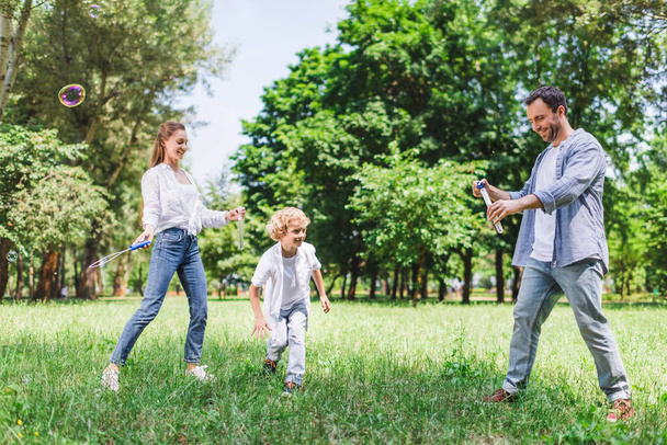 anya, apa és fia szappanbuborékok játszanak a parkban - Fotó, kép