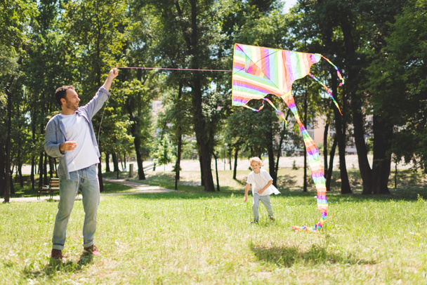 isä ja suloinen poika leikkii colofrul lentävät leija puistossa
 - Valokuva, kuva