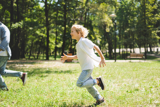 happy son running with father in park during daytime - Фото, зображення