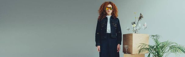 panoramic shot of redhead girl near wooden boxes, glasses and plants on grey with copy space - Foto, Bild