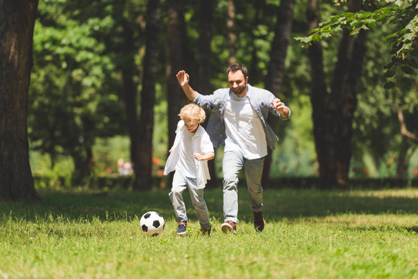 yakışıklı baba ve sevimli oğlu parkta futbol oynuyor - Fotoğraf, Görsel