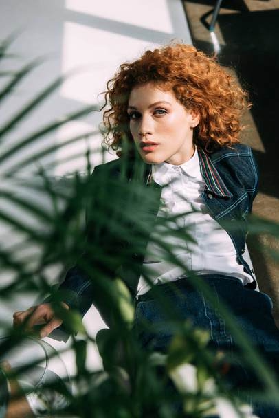 selective focus of stylish redhead girl posing near green leaves - Foto, immagini