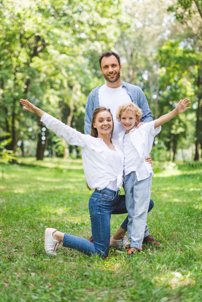 happy family with outstretched hands looking at camera in park - Photo, Image
