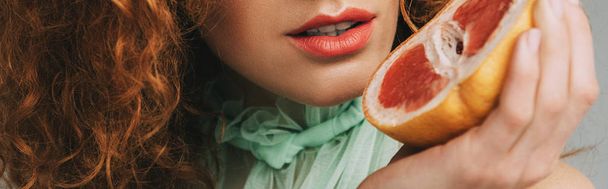 グレープフルーツでポーズをとる赤毛の女性のパノラマショット - 写真・画像