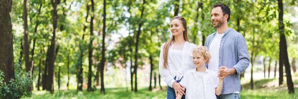panoramic shot of happy family holding hands in park with copy space - Fotografie, Obrázek