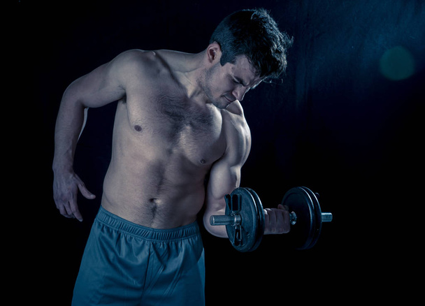 Portret van jonge gespierde atleet man uit te werken oefeningen en poseren met dumbbells, bodybuilder mannelijk naakte torso tillen gewichten in fitness sport lichaamsverzorging en gezonde levensstijl. - Foto, afbeelding