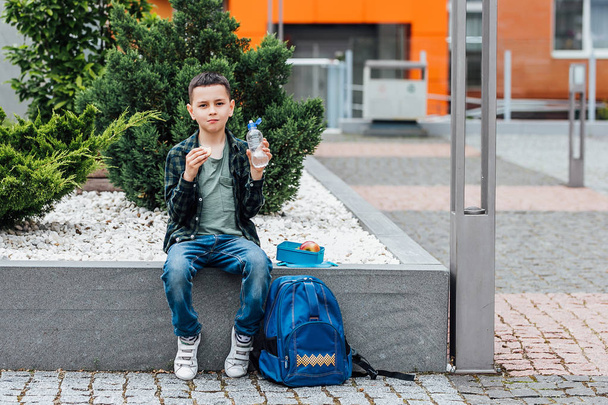 Cute boy eating from lunch box, focus on foreground - Фото, изображение