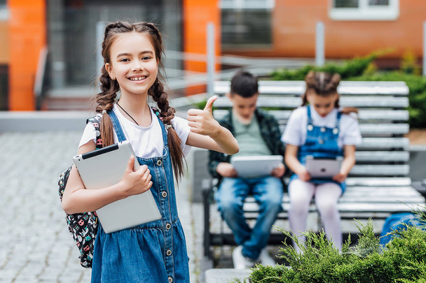girl with digital tablet near school, okay sign, selective focus - Фото, изображение