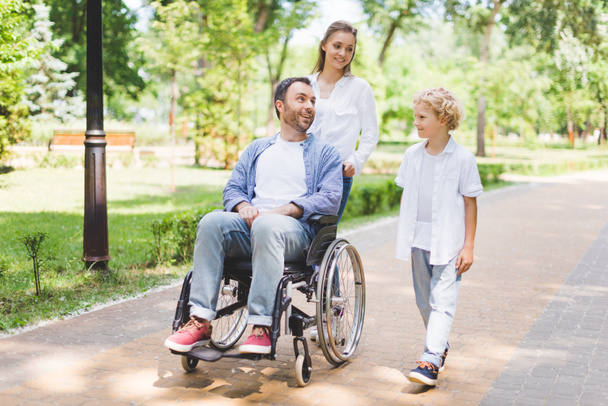 parkta tekerlekli sandalyede engelli babası ile anne ve sevimli oğlu - Fotoğraf, Görsel
