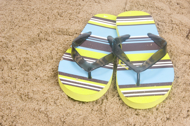 Zapatillas verdes de verano tumbadas sobre arena
 - Foto, imagen