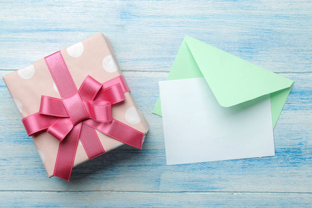 une enveloppe multicolore avec un en-tête d'inscription et une boîte cadeau sur une table en bois bleu. vue de dessus
 - Photo, image