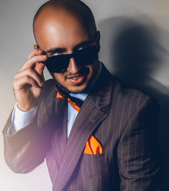 Beautiful man in sunglasses looking away on gray background - Zdjęcie, obraz