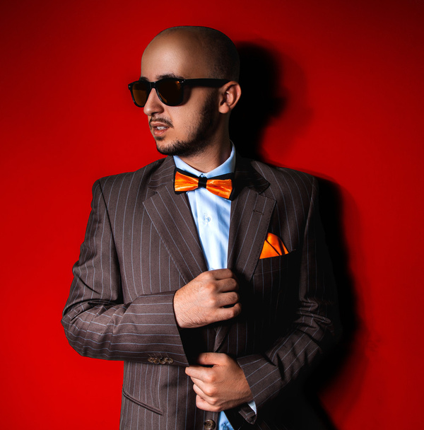 Nice man in sunglasses and suit on red background - Foto, Bild