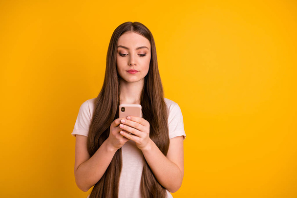 Close up photo beautiful amazing she her lady very long hairstyle hold hands arms telephone not smiling read political news clever person wear casual pastel t-shirt isolated yellow bright background - Fotó, kép