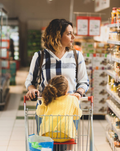 Moeder en dochter winkelen voor boodschappen in supermarkt. - Foto, afbeelding