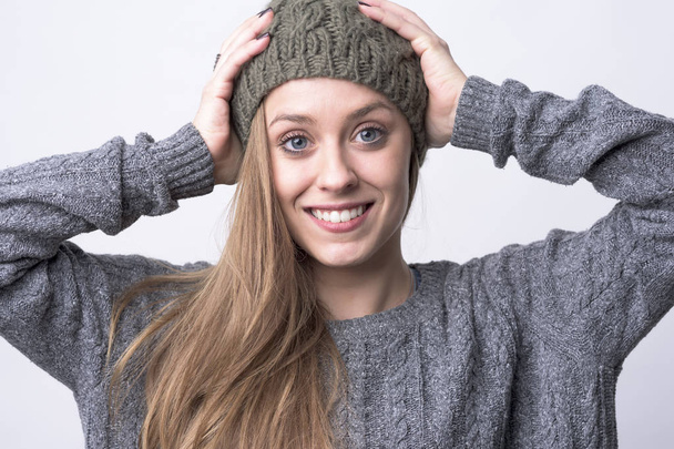 Portrait of young beautiful woman wearing knitted cap with white toothy healthy smile on light gray background.  - Fotografie, Obrázek