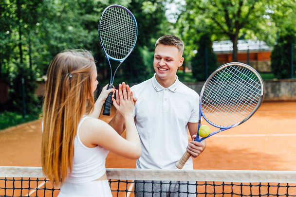 Young couple with tennis rackets standing on court   - Foto, imagen