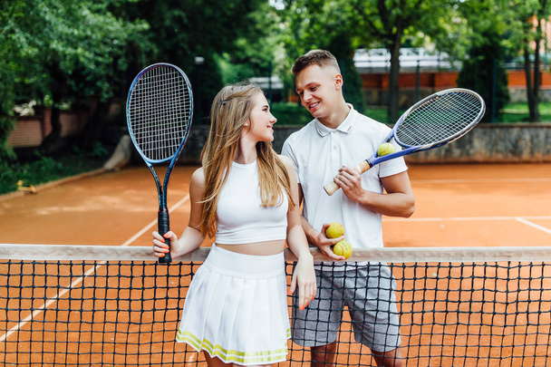 couple relaxing after playing game of tennis outside  - Foto, afbeelding