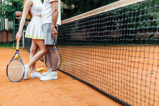 couple legs in tennis court holding on hands racket - Foto, Imagen