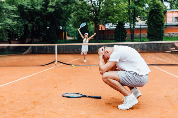 young couple playing tennis game outdoor, man losing  - Zdjęcie, obraz