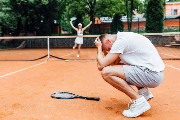 young couple playing tennis game outdoor, man losing   - Fotó, kép