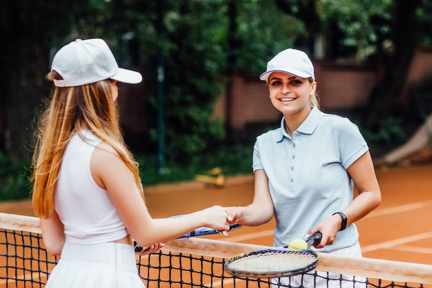 Photo of cute young female tennis players greeting with trainer on tennis court  - Φωτογραφία, εικόνα