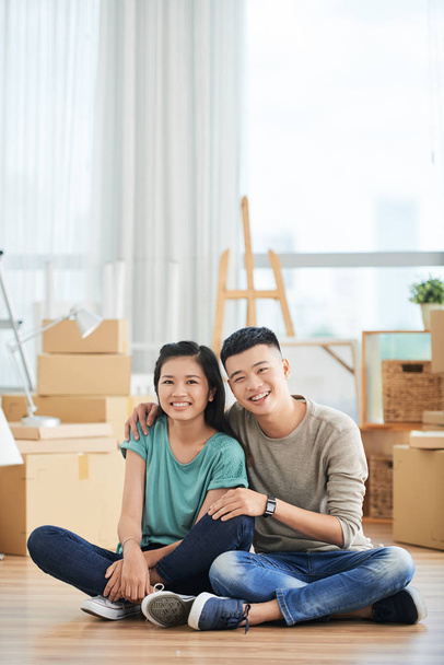 Щаслива молода азіатська пара відпочиває на підлозі в новій квартирі вони переїхали в - Фото, зображення