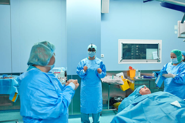 Chirurg provádějící kosmetickou operaci na operačním sále nemocnice. Chirurg v masce s loupáním během lékařské prohlídky. Zvětšení prsou - Fotografie, Obrázek