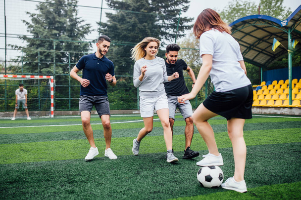 Young men and women playing soccer game outdoors - Fotó, kép