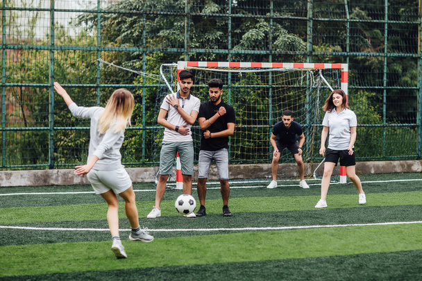 Young men and women playing soccer game outdoors - Foto, immagini