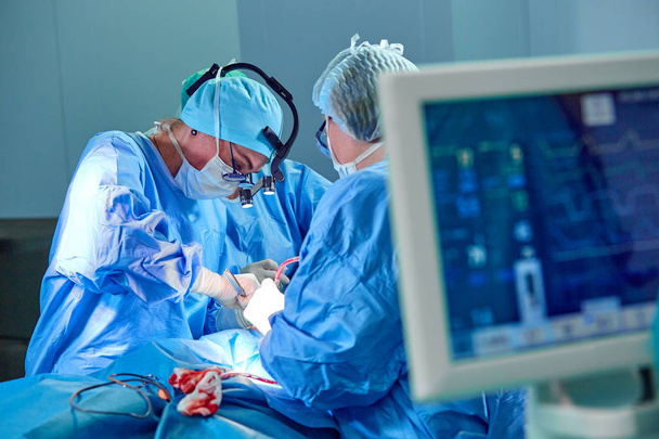 Ηλεκτροκαρδιογράφημα στο νοσοκομείο χειρουργική επέμβαση στα επείγοντα περιστατικά δείχνει καρδιακό ρυθμό του ασθενούς με θολή ομάδα χειρουργών φόντο - Φωτογραφία, εικόνα