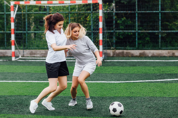 Two young female soccer players on field  - Фото, изображение