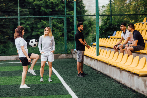 friends playing soccer at stadium, women with ball in foreground - Φωτογραφία, εικόνα