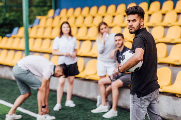 friends at football field, man with ball in foreground - Фото, зображення