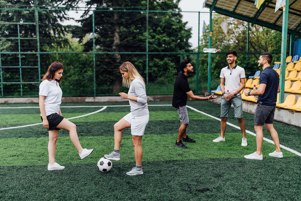 friends playing soccer at stadium, women with ball in foreground - Φωτογραφία, εικόνα