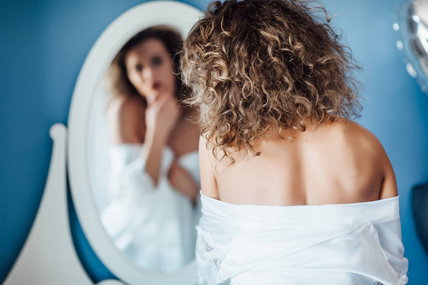 Focus at woman back, pretty woman looking at mirror - Foto, afbeelding