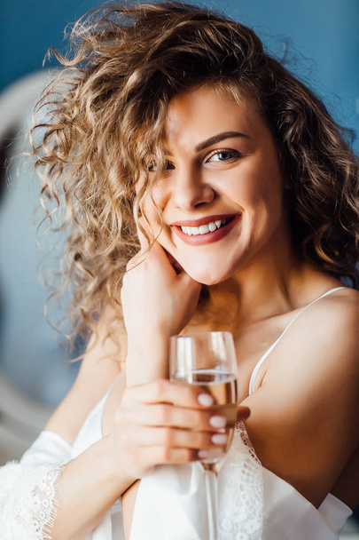 smiling woman with curly hair drinking champagne - Фото, изображение
