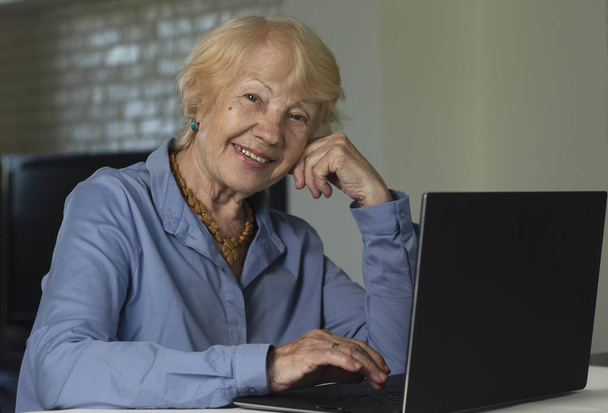 Mulher de cabelos grisalhos com portátil. Idosa escrevendo memórias no laptop, procurando informações na Internet ou se comunicando online
 - Foto, Imagem