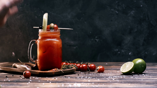 vista ritagliata di donna mettendo sedano bastone e stuzzicadenti con olive in sanguinoso cocktail Mary vicino pomodorini su nero
  - Filmati, video