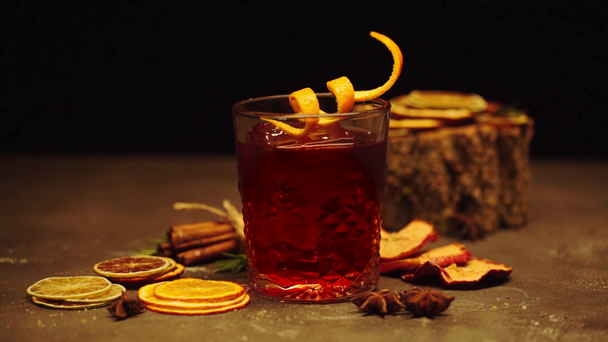appelsiininkuori lasissa alkoholin cocktail lähellä kuivattuja hedelmiä mustalla
  - Materiaali, video