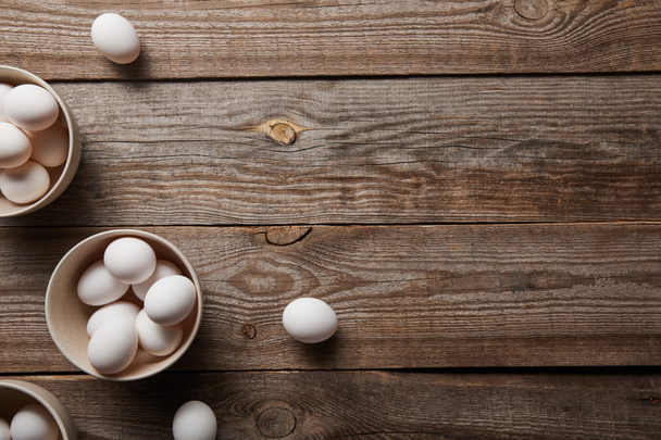 top view of chicken eggs in bowls on wooden table - Fotoğraf, Görsel