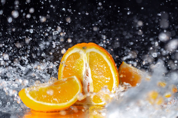 Arancione con spruzzi d'acqua su sfondo nero con acqua in streaming su di esso
. - Foto, immagini
