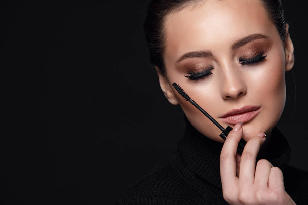 Beauty Cosmetics.Woman applying black mascara on eyelashes with makeup brush. photos of appealing brunette girl on black background.High Resolution - Foto, Imagem
